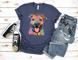 Navy t-shirt with colorful dog graphic, black sneakers, and jeans on a wooden surface