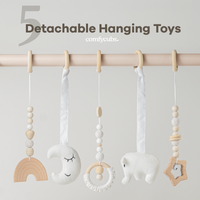 Detachable hanging toys with wooden and fabric elements on a rod against a light gray background.