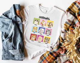 White t-shirt with cat-themed design and text 'cattitudes' on a white background with denim jacket and plaid scarf.