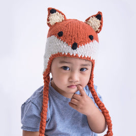 Child wearing a fox-themed knitted hat with a white background