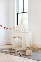 Children's play area with a white play tent, toys, and a small table in a room with large windows.