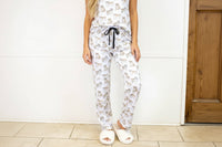 A person wearing white pajamas with a bulldog pattern, including a top and bottom, standing indoors.