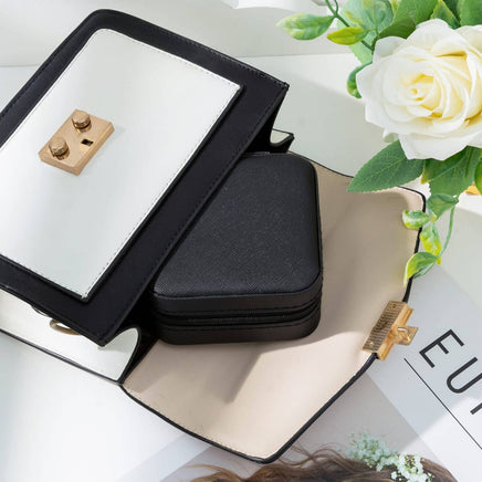 Black jewelry case with mirror on a white surface with flowers