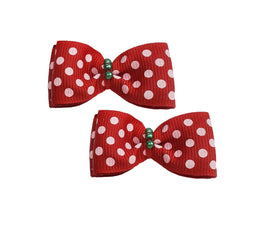 Two red polka dot hair bows with green centers on a white background