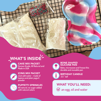Cake making kit with cake mix packets, silicone pan, birthday candle, and sprinkles on a wooden surface.