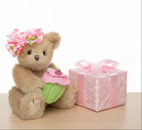 Teddy bear with a pink flower headband and cupcake outfit on a white background