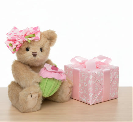 Teddy bear with a pink flower headband and cupcake outfit on a white background