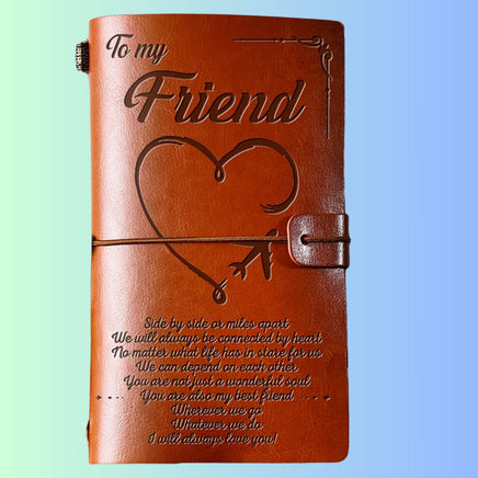 Brown leather journal with engraved text and heart design on a light blue background
