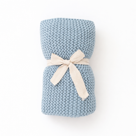 Blue hand knitted blanket with a white bow on a white background