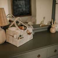 Baby items including a basket with toys and bottles on a dresser.