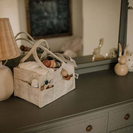 Baby items including a basket with toys and bottles on a dresser.