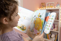 little girl reading a book with her universal voice recorder. 