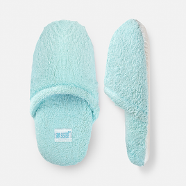 A pair of light blue terry spa slippers with a plush exterior and a non-slip sole.