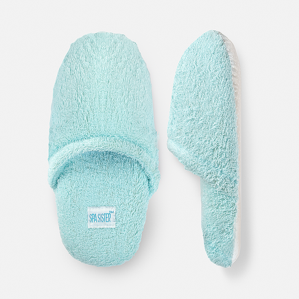 A pair of light blue terry spa slippers with a plush exterior and a non-slip sole.