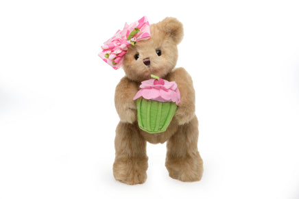 Plush teddy bear with a pink flower headband and cupcake toy on a white background