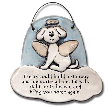 Ceramic memorial plaque shaped like a white angel dog with wings and a halo, sitting on a light blue cloud-shaped background with a hanging loop at the top. The lower cloud area has engraved black text reading, 'If tears could build a stairway and memories a lane, I'd walk right up to heaven and bring you home again.