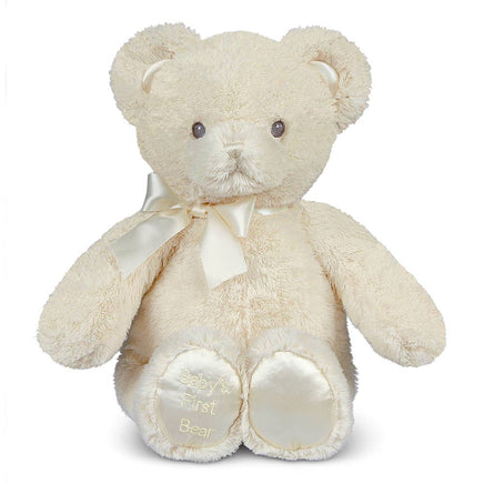 Cute teddy bear with a bow tie on a white background. His foot has an embroidered massage that says Baby's First Bear