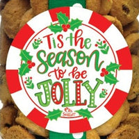 Three jars of dog treats with Christmas-themed labels and bows on a white background