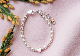 Pearl bracelet with a heart charm on a pink background