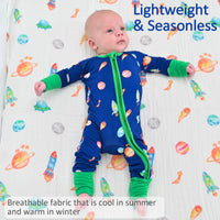 Baby wearing a blue onesie with colorful patterns on a white background with space-themed designs.