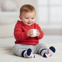 baby holding a baseball and wearing baby socks with baseball design on a white background