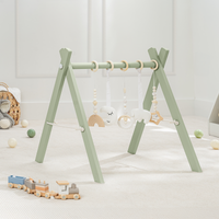 baby play gym with hanging toys on a light wooden floor. in sage or blush