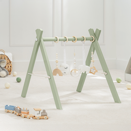 baby play gym with hanging toys on a light wooden floor. in sage or blush