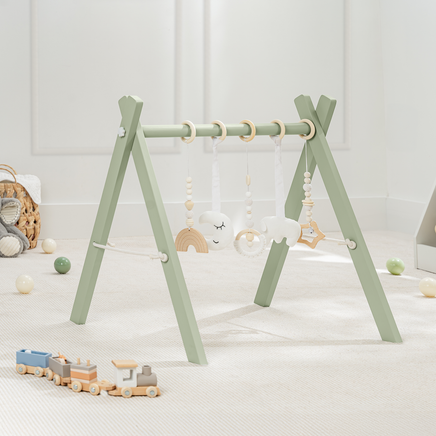 baby play gym with hanging toys on a light wooden floor. in sage or blush