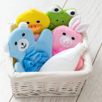 Set of colorful animal-themed bath toys in a basket on a light wooden surface.