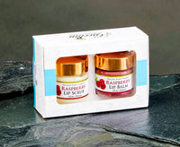 Two raspberry lip products in a box on a dark surface