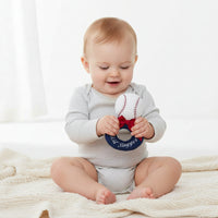 Baseball-shaped toy with a red bow and 'Lil' Slugger' text on a white background