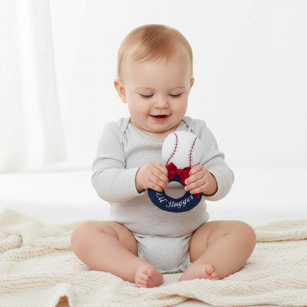 Baseball-shaped toy with a red bow and 'Lil' Slugger' text on a white background