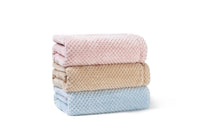 Stack of three folded towels in pink, beige, and blue on a white background