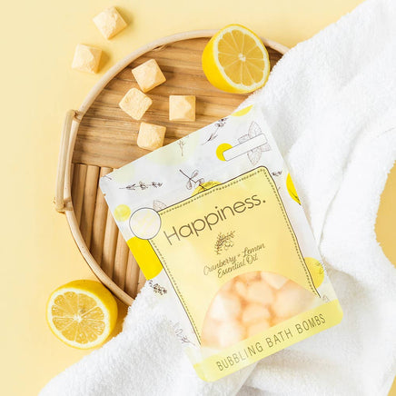 Pack of bubbling bath bombs with lemon slices and a towel on a yellow background