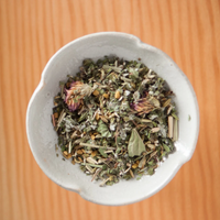 White bowl filled with dried herbs on a wooden surface