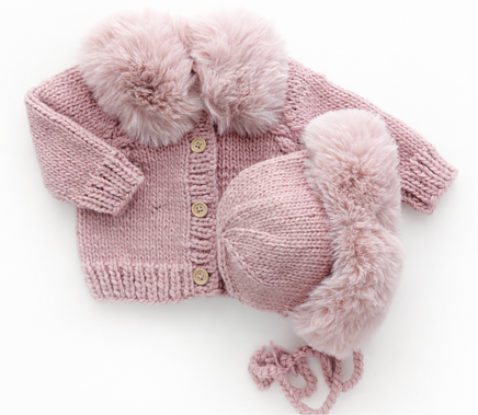Pink knitted baby set with fur trim on a white background