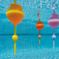 Colorful wine glasses floating in clear blue water