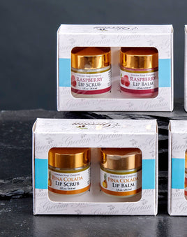 Four sets of lip scrubs and lip balms in packaging on a dark surface.