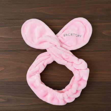 Pink plush scrunchie with bunny ears on a wooden surface