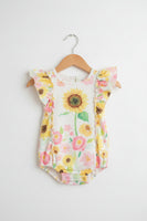 A baby romper with a yellow, pink, and green floral sunflower print, hanging on a white plastic hanger against a plain light background.