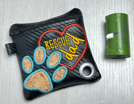 Black pouch with embroidered 'Rescue Dad' text and paw prints next to a green trash bag on a light gray background