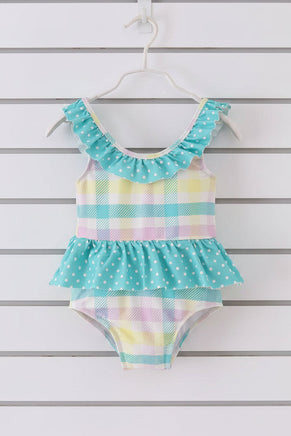 little girls one-piece swimsuit with pastel colors and ruffled details on a white background